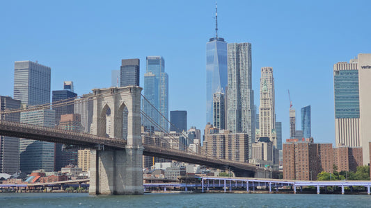 Brooklyn Bridge and Lower Manhattan skyline featuring One World Trade Center on a sunny day.